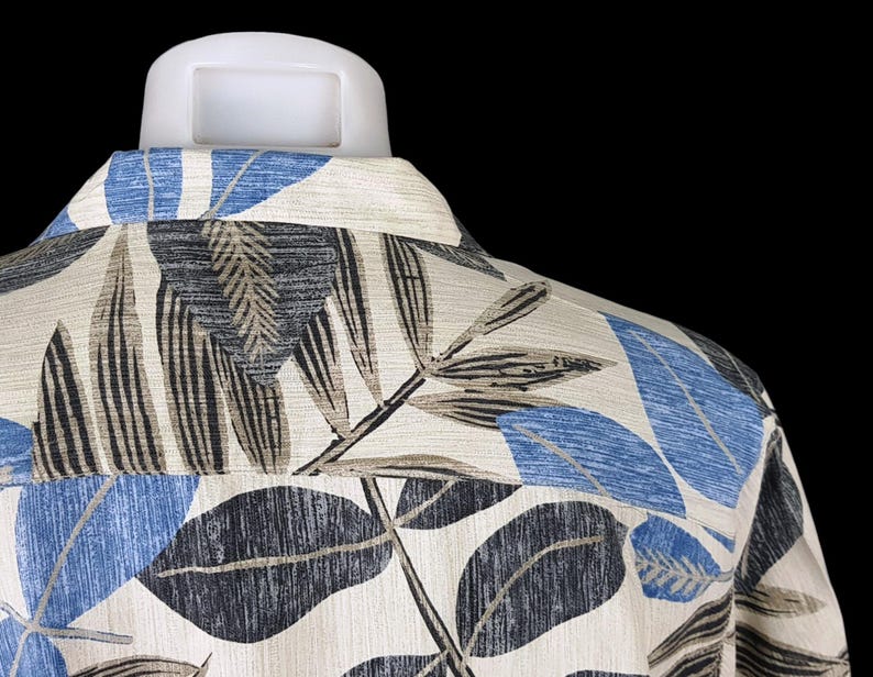 May include: A white shirt with a blue and brown leaf pattern. The shirt is made of a soft, textured fabric.