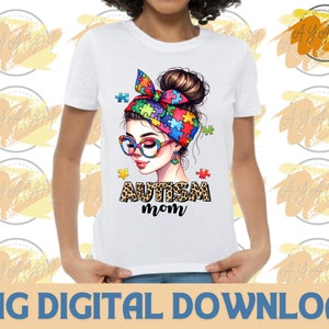 Pu&ograve; includere: Maglietta bianca con un design a puzzle colorato e il testo "Autism Mom" in nero e stampa leopardata marrone.