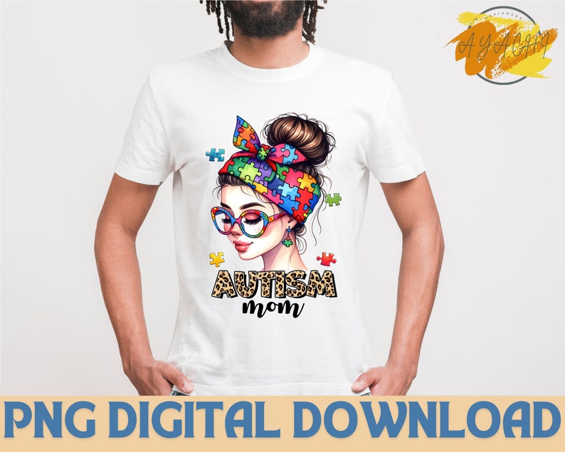 Pu&ograve; includere: Una maglietta bianca con un'illustrazione colorata di una donna con una fascia di pezzi di puzzle e il testo "Autism Mom" in stampa leopardata.