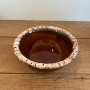 Op de afbeelding: Een kleine bruine en witte keramische kom met een gespikkeld glazuur.
