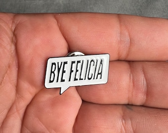 Op de afbeelding: Een witte emaille pin met een zwarte omtrek in de vorm van een spreekballon. De tekst "BYE FELICIA" is in zwart in de spreekballon gedrukt.
