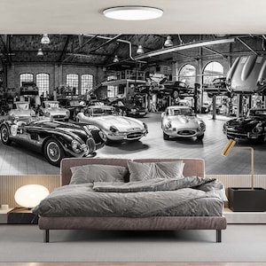 Peut inclure: Photographie en noir et blanc d'un garage de voitures anciennes avec plusieurs voitures classiques, dont une Jaguar E-Type, une Jaguar XK120 et une Jaguar XK150. Les voitures sont toutes en cours de réparation et de restauration.