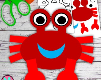 Op de afbeelding: Rode papieren knutselkrab met een blauwe glimlach, grote zwarte ogen en gesegmenteerde poten. De knutselset bevat een printbaar sjabloon.