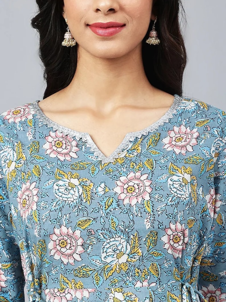 May include: A blue floral print top with a V-neck and a silver trim around the neckline.