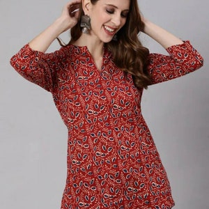 May include: A red, blue and white patterned tunic top with a V-neck and three-quarter sleeves.