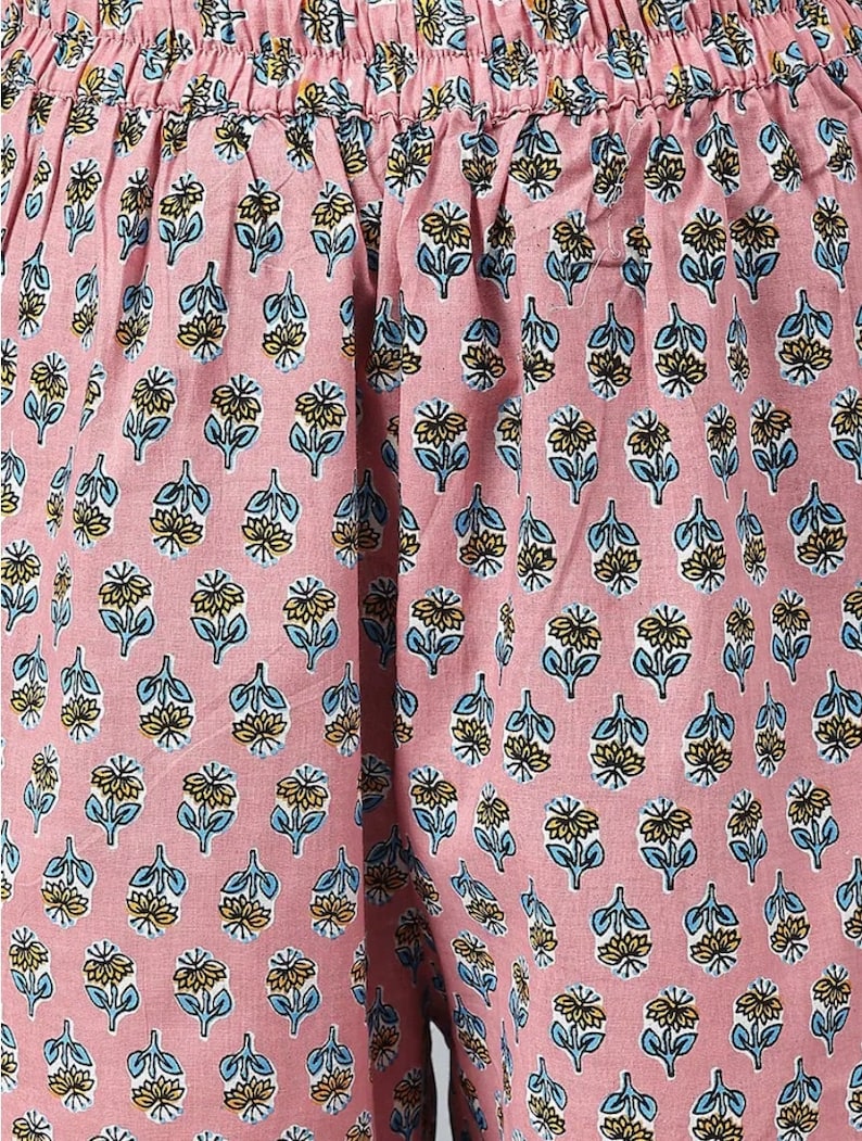 May include: Pink fabric with a floral pattern. The pattern features small blue and yellow flowers on a pink background.