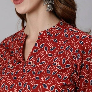 May include: A red and blue floral print top with a V-neckline. The top features a traditional Indian design with small leaves and flowers.