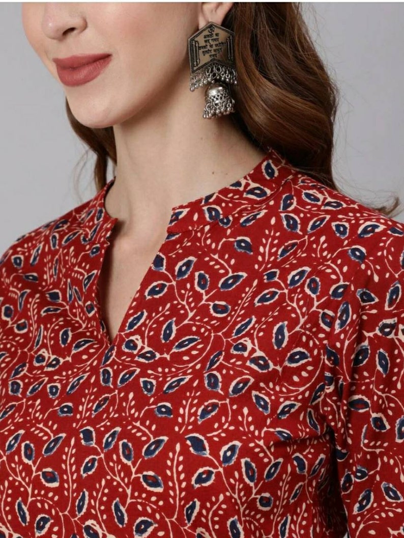 May include: A red and blue floral print top with a V-neckline. The top features a traditional Indian design with small leaves and flowers.