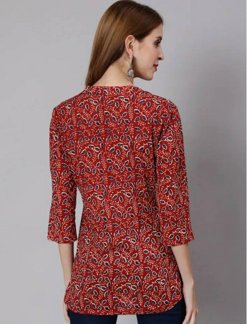 May include: A red, blue and cream patterned tunic top with a V-neck and three-quarter sleeves.