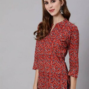 May include: A red, long-sleeved top with a blue and white floral pattern. The top has a V-neck and a side slit.