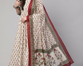 May include: Cream-colored Indian suit with a floral pattern in red and green. The suit includes a long tunic, matching scarf, and pants. The scarf has a red border and floral design. The outfit is suitable for casual or festive occasions.