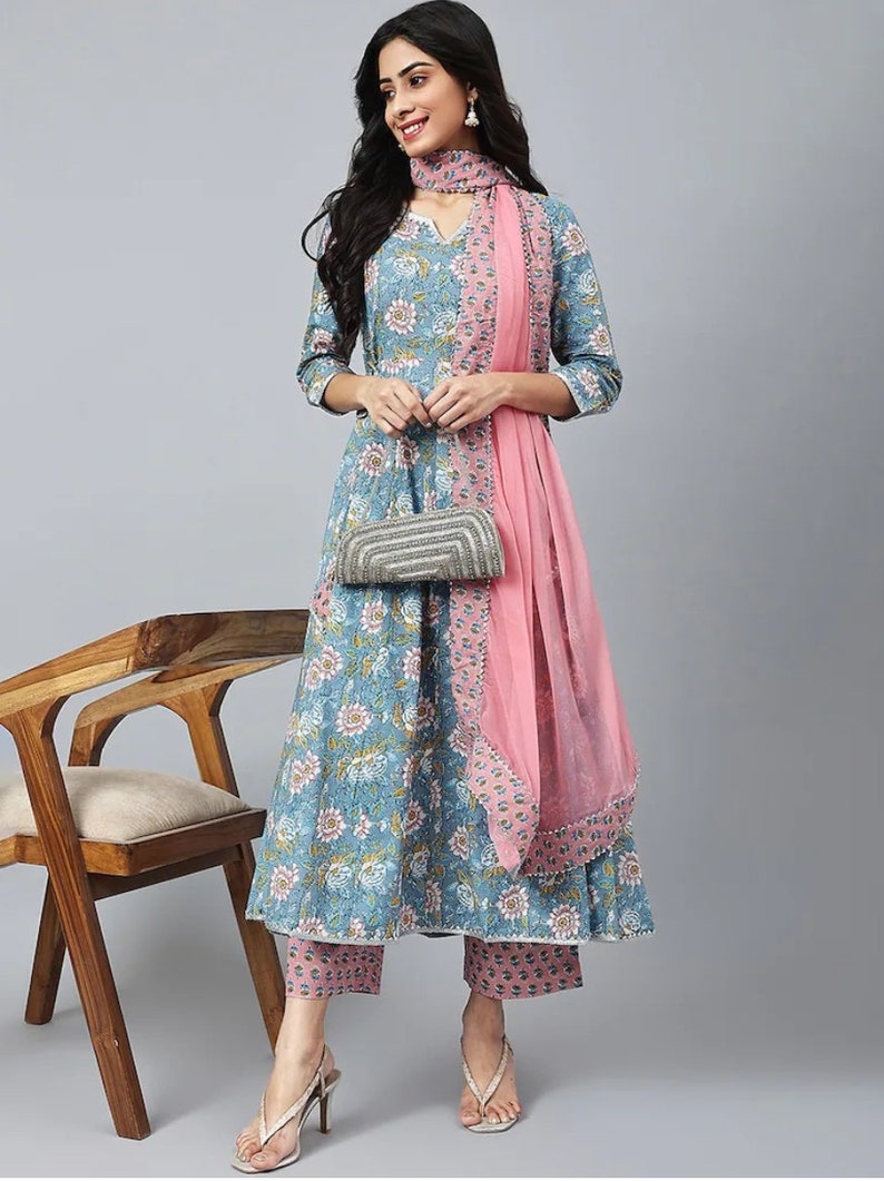 May include: A blue and pink floral print kurta with matching pants and a pink dupatta. The kurta has a V-neck and three-quarter sleeves. The pants are ankle-length and the dupatta is sheer with a beaded border.