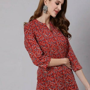 May include: A red, blue and white patterned tunic top with a V-neck and three-quarter sleeves.