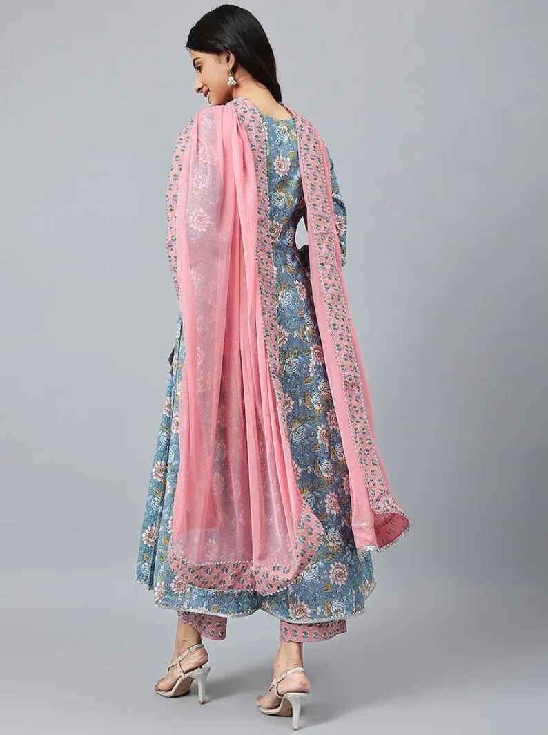 May include: A blue and pink floral print dress with a matching pair of pants and a pink sheer dupatta. The dress has a long, flowing skirt and a fitted bodice. The dupatta is draped over the shoulders and has a delicate floral border.