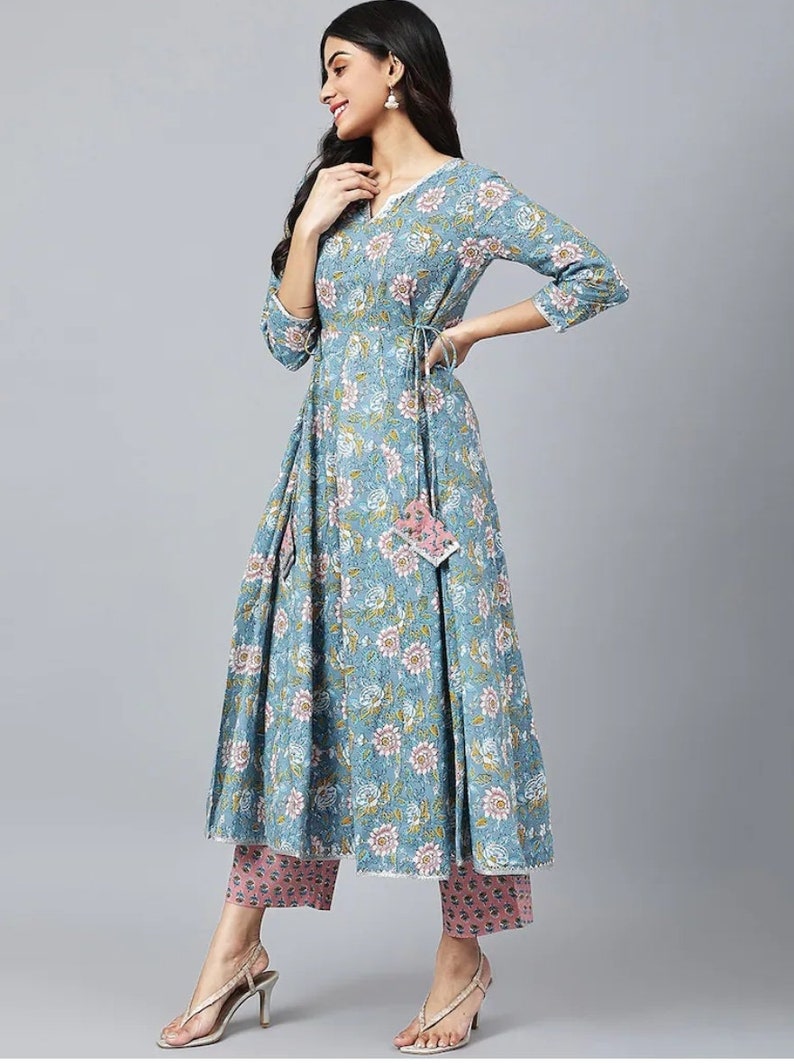May include: A blue floral print dress with a tie at the waist and matching pink pants. The dress has a V-neck and three-quarter sleeves.