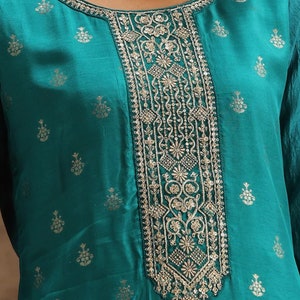 May include: Teal blue top with a silver embroidered neckline. The neckline features a floral design with sequins.