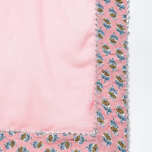 May include: Pink fabric with a floral print border. The border has a silver trim.