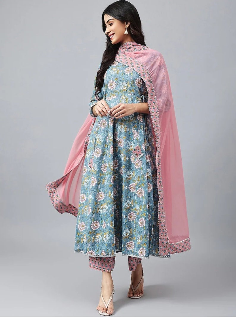 May include: A blue floral print dress with a pink dupatta. The dress has a round neckline and three-quarter sleeves. The dupatta has a lace border and is made of a sheer fabric.