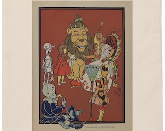 Op de afbeelding: Een witte tote bag met een rode en gele illustratie van de personages uit The Wizard of Oz. De illustratie toont Dorothy, de Vogelsverschrikker, de Tin Man, de Cowardly Lion en Glinda the Good Witch. De tekst onder de illustratie luidt "They went on and on to the Golden City."
