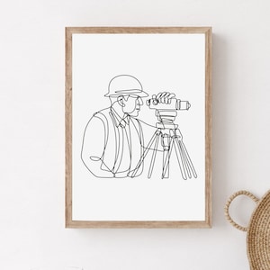 Peut inclure: Dessin au trait d'une personne portant un casque et utilisant un instrument de topographie. Le dessin est en noir et blanc et est encadré dans un cadre en bois clair.