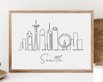 May include: A black and white line drawing of the Seattle skyline, including the Space Needle, the Ferris wheel, and other buildings. The drawing is on a white background and is framed in a wooden frame. The text "Seattle" is written below the drawing.