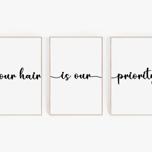 May include: Three white framed prints with black text that reads "your hair is our priority".