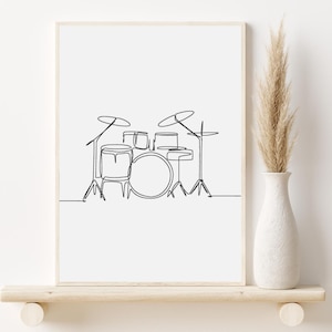 Può includere: Una stampa artistica minimalista incorniciata con un disegno a linea continua di una batteria. La linea nera è su sfondo bianco. La stampa è esposta su una mensola di legno con un vaso bianco e fiori secchi.