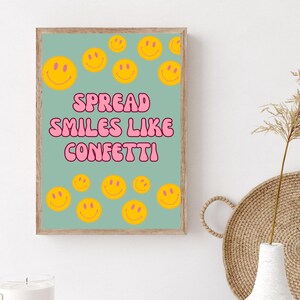May include: A light blue poster with the text "SPREAD SMILES LIKE CONFETTI" in pink bubble letters. The poster is decorated with yellow smiley faces.