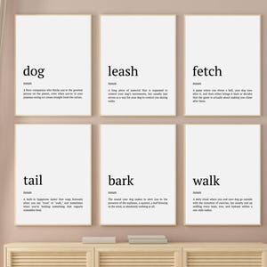 May include: Six black and white minimalist prints with definitions of dog-related words: dog, leash, fetch, tail, bark, and walk. The prints are framed and hung on a light brown wall.