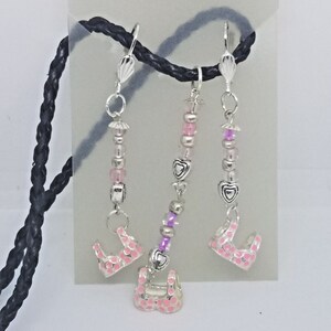 Könnte beinhalten: Drei silberne Charm-Halsketten mit rosa und violetten Perlen. Jede Halskette hat einen silbernen Herz-Anhänger und einen rosa BH-Anhänger.