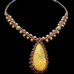 May include: A brown macrame necklace with a teardrop-shaped yellow stone pendant and green beads.
