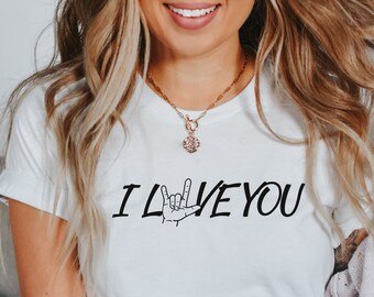 May include: White t-shirt with the text "I LOVE YOU" in black lettering. The word "LOVE" is depicted in American Sign Language.