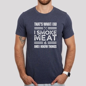 May include: A navy blue t-shirt with a white distressed graphic that reads "That's what I do I smoke meat and I know things".