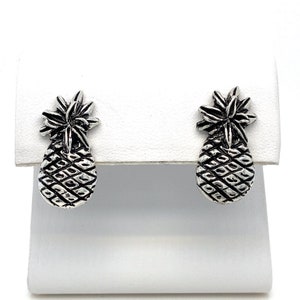 May include: A pair of silver pineapple stud earrings. The earrings are small and delicate, and they feature a detailed pineapple design.