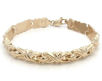 May include: A gold-toned bracelet with a detailed, interwoven design. The bracelet has a clasp closure.