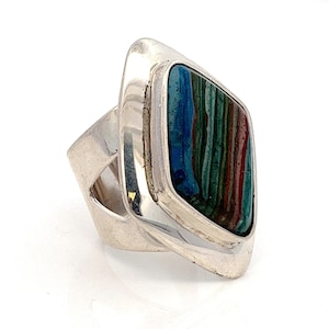 May include: A silver ring with a colorful, multi-layered stone set in a square shape.