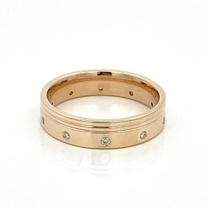 May include: A gold band ring with a double groove and small diamonds set around the band.