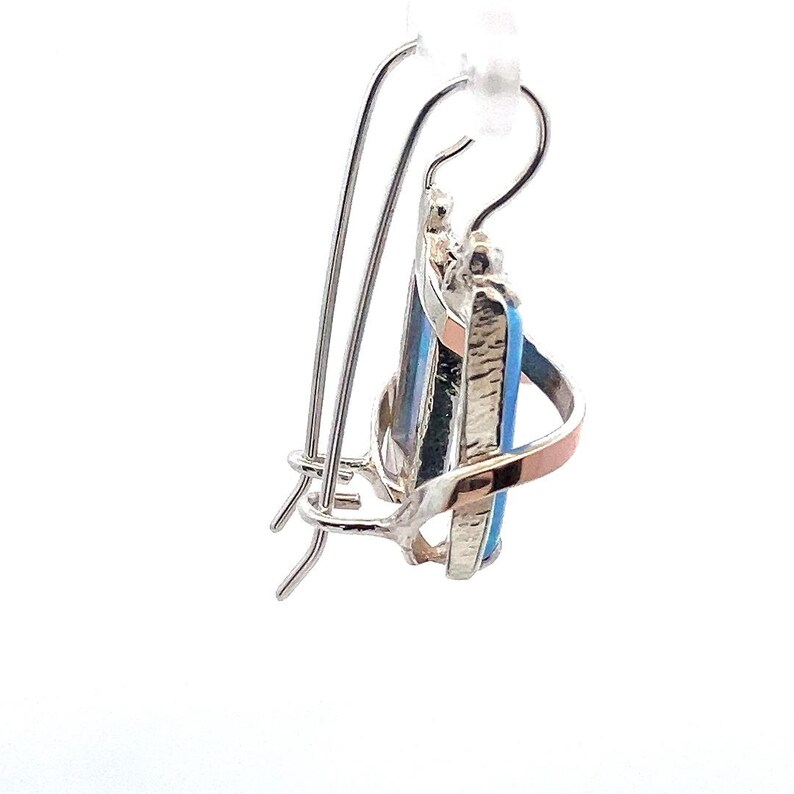 May include: Silver and gold tone earrings with a blue and black gemstone. The earrings have a hook closure.