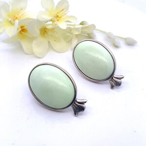 May include: A pair of silver tone clip-on earrings with oval shaped light green stones.