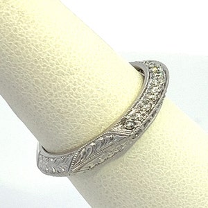 May include: A silver band ring with a delicate floral design and a row of small diamonds around the top edge.
