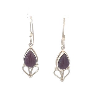 May include: A pair of silver dangle earrings with a teardrop-shaped purple stone set in each earring.