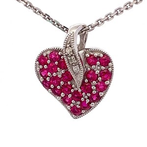 May include: A silver heart-shaped pendant necklace with a white gold chain. The pendant is set with small red rubies and a few small diamonds.