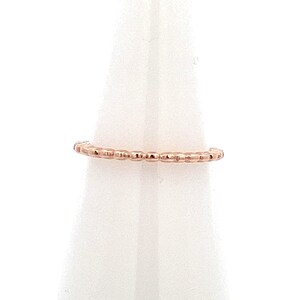 May include: A delicate rose gold ring with a beaded design. The ring is thin and features a series of small, evenly spaced beads around the band. The ring is displayed against a white background.