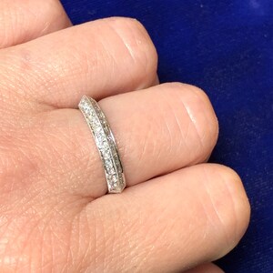 May include: A thin silver band with a row of small diamonds set in a channel setting.