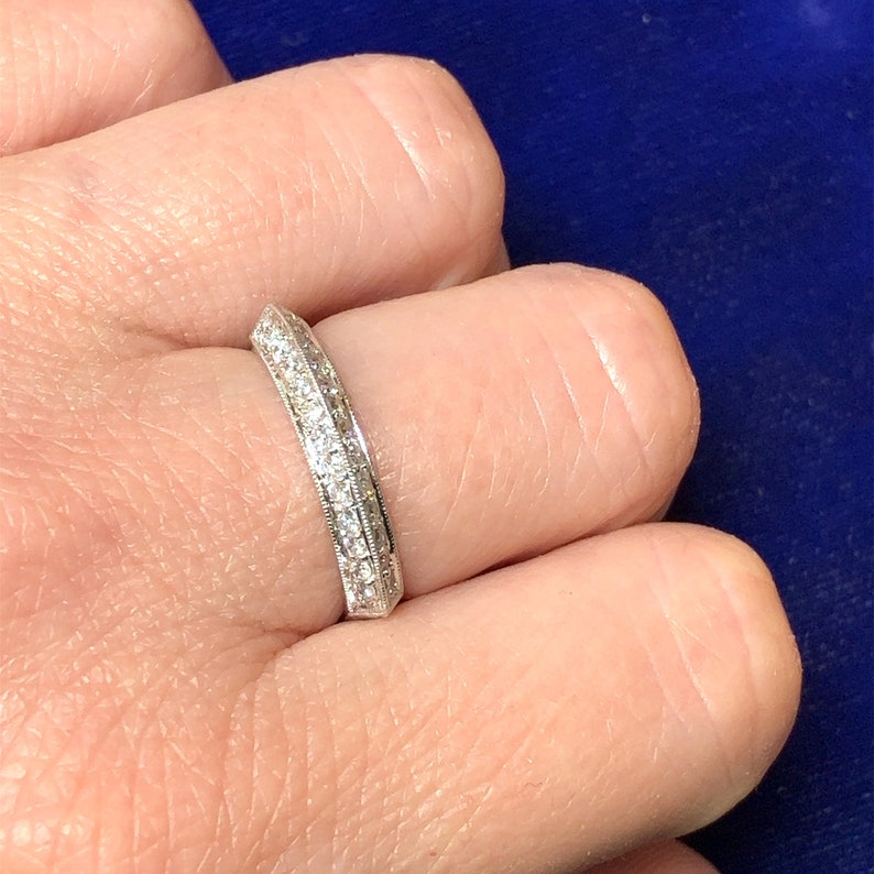 May include: A thin silver band with a row of small diamonds set in a channel setting.