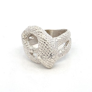 May include: A silver ring with a snake design. The snake is coiled and has a textured surface.