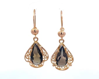 May include: A pair of rose gold earrings. Each earring features a teardrop-shaped, smoky quartz gemstone set within a filigree frame. The earrings have a small ball accent and a hook closure.