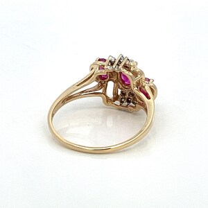 May include: A gold ring featuring a cluster of red rubies and small diamonds set in a delicate filigree design.