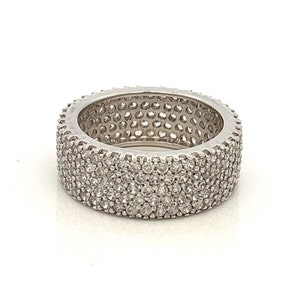 May include: A silver band ring with a wide band set with small, clear stones.
