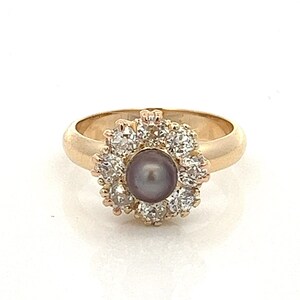 May include: A gold ring featuring a single grey pearl set within a halo of small diamonds.